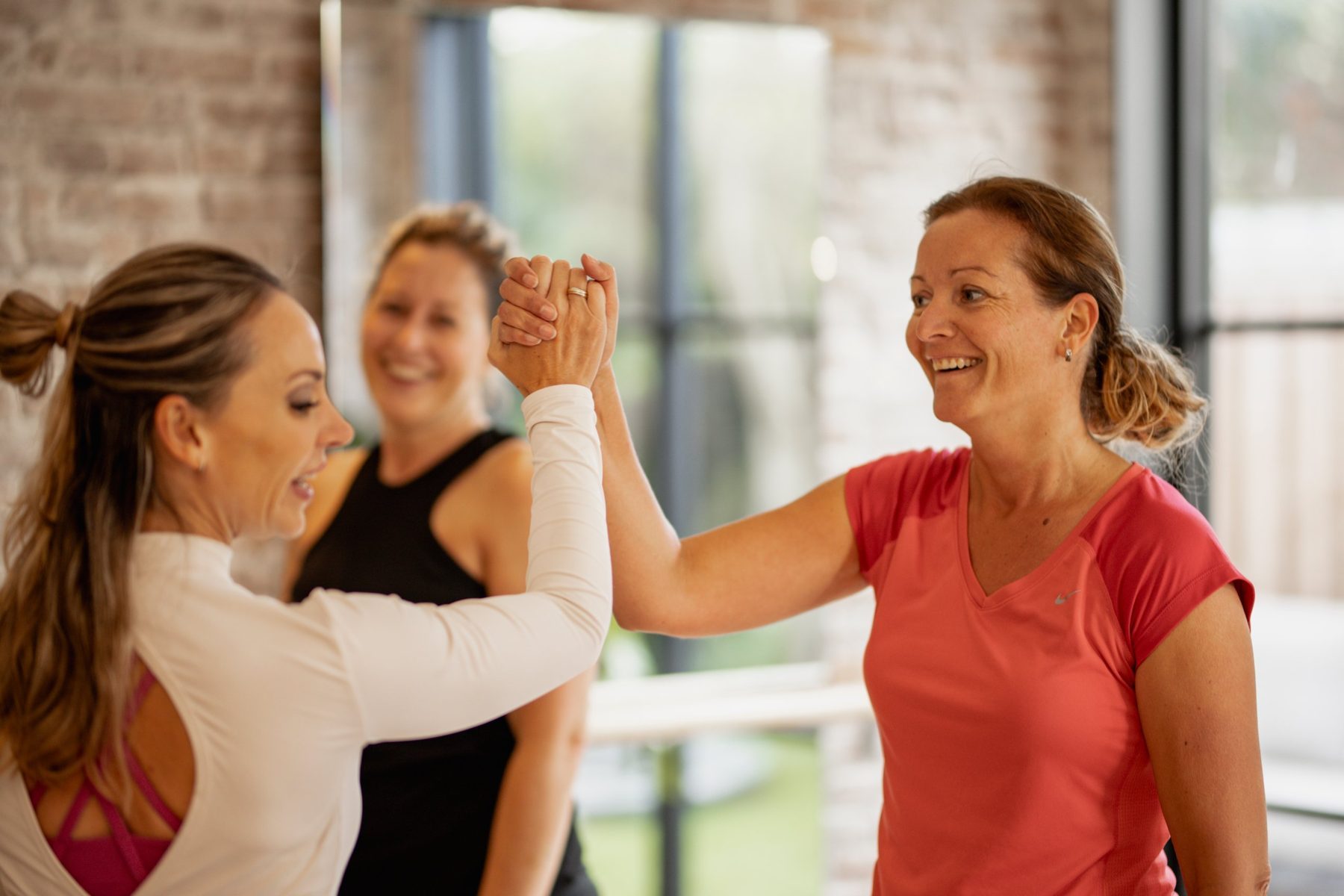 Joyce geeft een deelnemer een high five na de training, een andere deelnemer lacht mee